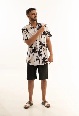 شاب سعودي بملابس صيفية يشير لجانبه خلفية بيضاء