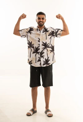 رجل سعودي مبتسم يستعرض عضلاته بملابس صيفية