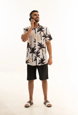 رجل سعودي يتحدث بالهاتف بملابس صيفية كاجوال