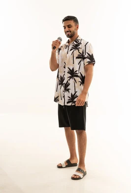 رجل سعودي يمسك ميكروفون بملابس صيفية كاجوال