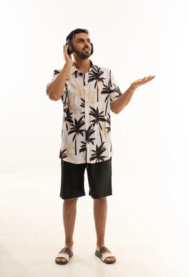 رجل عربي يرتدي سماعات وقميص صيفي بنقشة النخيل