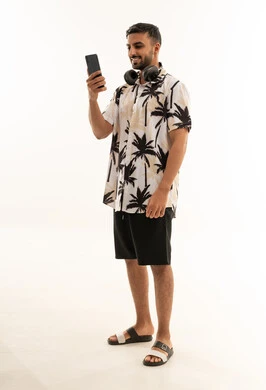 شاب سعودي يستخدم هاتف ذكي بملابس صيفية كاجوال