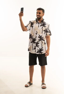 رجل عربي بملابس صيفية يلتقط سيلفي بالهاتف