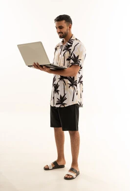 رجل سعودي يحمل لاب توب بملابس صيفية كاجوال
