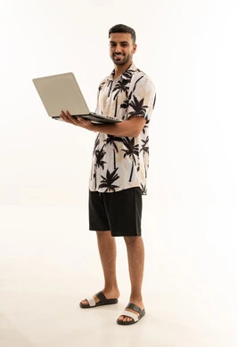 رجل عربي بملابس صيفية يحمل جهاز حاسوب محمول