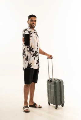 مسافر سعودي يحمل هاتفاً ذكياً مع حقيبة سفر