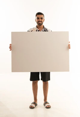 رجل سعودي يحمل لوحة بيضاء فارغة أمام خلفية بيضاء