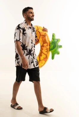 رجل سعودي يحمل عوامة مسبح بشكل أناناس بخلفية بيضاء