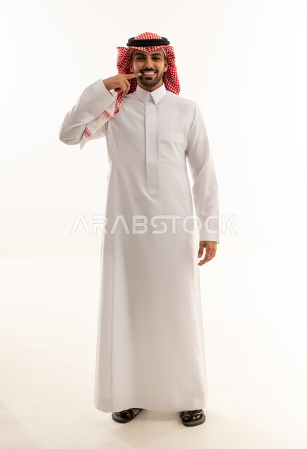 رجل سعودي بالزي التقليدي يشير إلى أسنانه