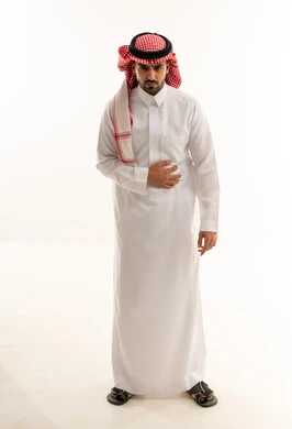 رجل سعودي بالثوب التقليدي يعاني من ألم في المعدة