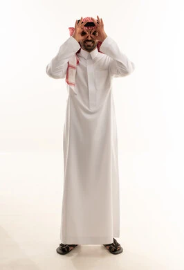 رجل سعودي بالزي التقليدي يشكل حركة منظار بيديه