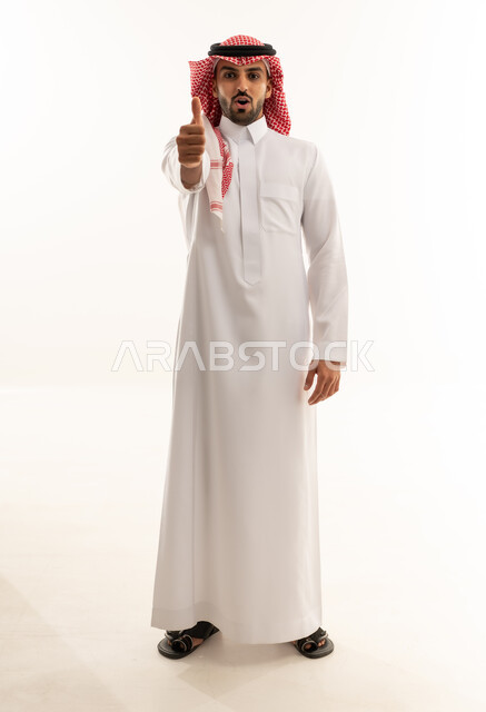 رجل سعودي بالثوب يرفع إبهامه على خلفية بيضاء