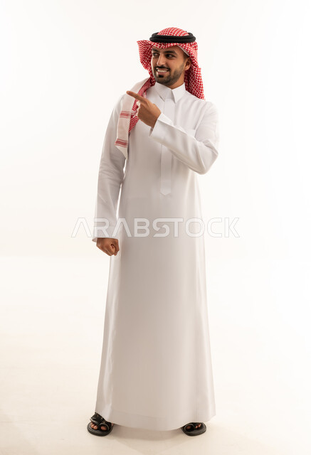 رجل سعودي بالثوب التقليدي يشير بيده على خلفية بيضاء