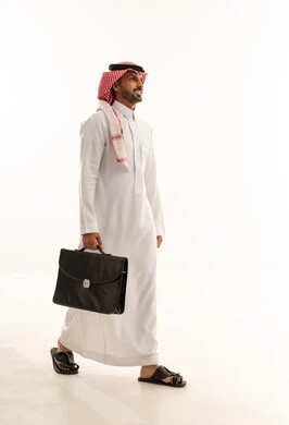 رجل أعمال سعودي يسير بحقيبة على خلفية بيضاء