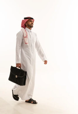 رجل أعمال سعودي يمشي بحقيبة عمل في الاستوديو