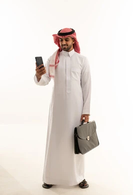 رجل أعمال سعودي بالثوب يحمل حقيبة وهاتف ذكي