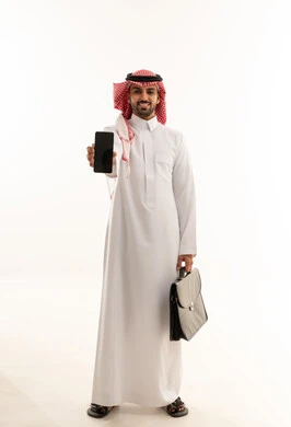 رجل أعمال سعودي يحمل هاتفاً ذكياً وحقيبة أعمال بخلفية بيضاء