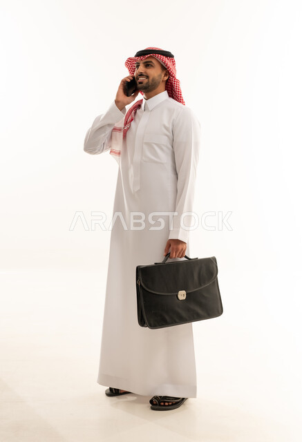 رجل أعمال سعودي مع حقيبة يتحدث بالهاتف