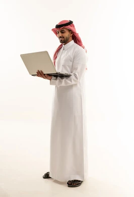 رجل سعودي بالزي التقليدي يستخدم اللابتوب