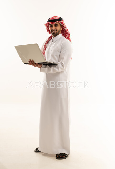 رجل سعودي بالثوب التقليدي يحمل جهاز محمول