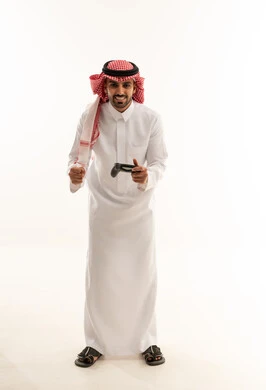 رجل سعودي يحمل جهاز تحكم ألعاب بخلفية بيضاء