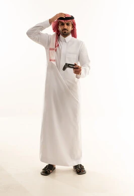 رجل سعودي مع جهاز تحكم ألعاب بخلفية بيضاء