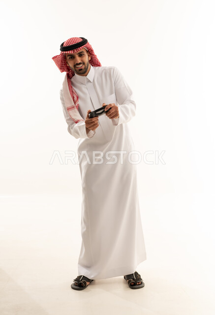 شاب سعودي بالزي التقليدي يمسك جهاز تحكم ألعاب