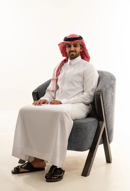 رجل سعودي بالزي التقليدي يجلس على كرسي