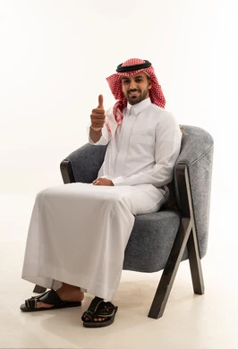رجل سعودي بالثوب يرفع إبهامه على خلفية بيضاء