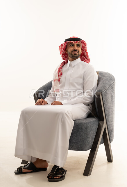 رجل سعودي بالزي التقليدي يجلس على كرسي عصري