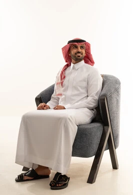 رجل سعودي بالزي التقليدي يجلس على كرسي عصري