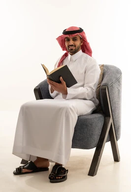 رجل سعودي بالزي التقليدي يقرأ كتاباً في استوديو