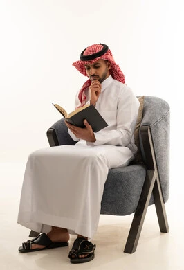 رجل سعودي بالثوب التقليدي يقرأ كتاباً