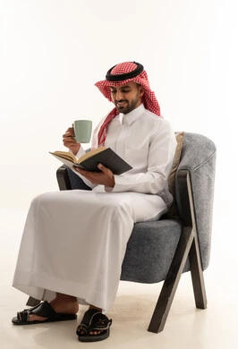 رجل سعودي بالزي التقليدي يقرأ كتاباً في الاستوديو