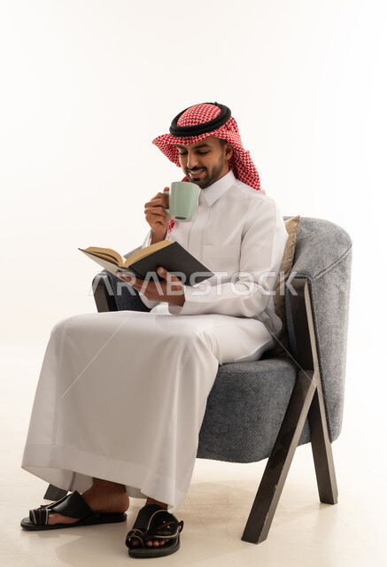 رجل سعودي بالثوب التقليدي يقرأ كتاباً