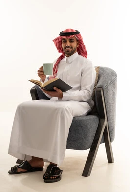 رجل سعودي بالزي التقليدي يقرأ كتاباً في استوديو