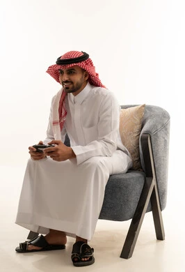 رجل سعودي بالثوب التقليدي يلعب ألعاب الفيديو
