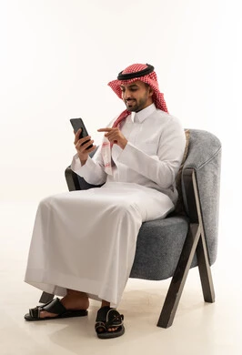 Saudi Man in Traditional Thobe Using Smartphone in Studio