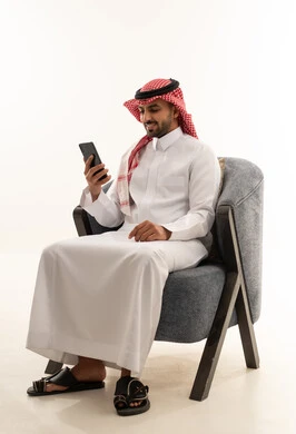 رجل سعودي بالثوب التقليدي يستخدم الهاتف الذكي
