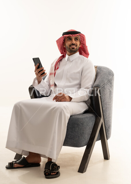 Saudi Man in Traditional Thobe Using Smartphone