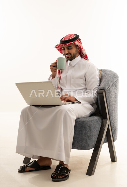 رجل سعودي يرتدي الثوب التقليدي يستخدم الحاسوب