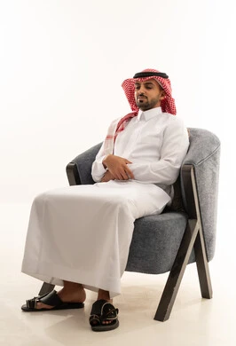 رجل سعودي بالزي التقليدي يجلس على كرسي عصري