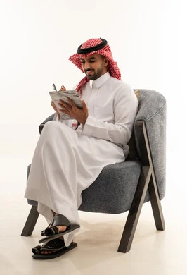 رجل سعودي بالزي التقليدي يكتب على لوحة ملاحظات