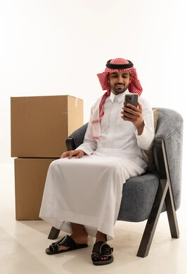 رجل سعودي يستخدم الهاتف الذكي بجانب صناديق شحن