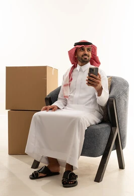 رجل سعودي مع هاتف ذكي وصناديق شحن