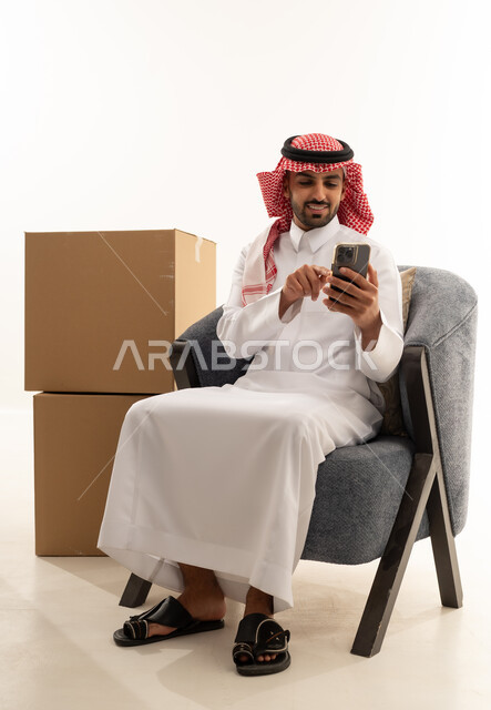 رجل سعودي يستخدم الهاتف الذكي بجانب صناديق شحن
