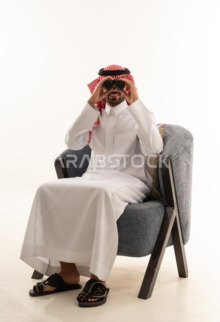 رجل سعودي بالثوب التقليدي يستخدم المنظار