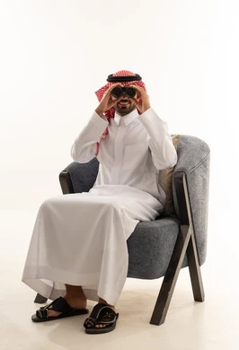 Saudi Man in Traditional Thobe Using Binoculars