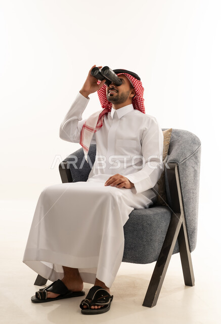 رجل سعودي بالثوب التقليدي يستخدم المنظار