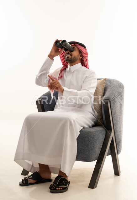 رجل سعودي بالثوب التقليدي ينظر عبر المنظار